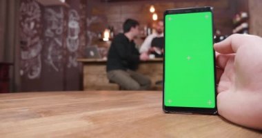 Adam ucuz vintage bir kafede yeşil ekran ile telefonda bira
