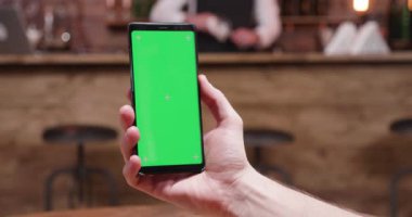 Adam yeşil ekran ile modern bir akıllı telefon tutar