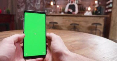 Bir adam ile bir yeşil ekran smartphone vintage bir barda el atış