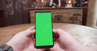 Handgeld atış erkek el ile yeşil perde smartphone üzerinde tutan