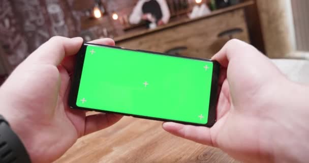 Handheld-Aufnahme von Kerl, der ein Green-Screen-Telefon hält und ein paar Videospiele darauf spielt — Stockvideo