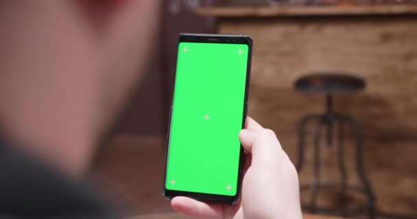 Sobre el hombro toma de mano del hombre mirando el teléfono con pantalla verde — Vídeos de Stock