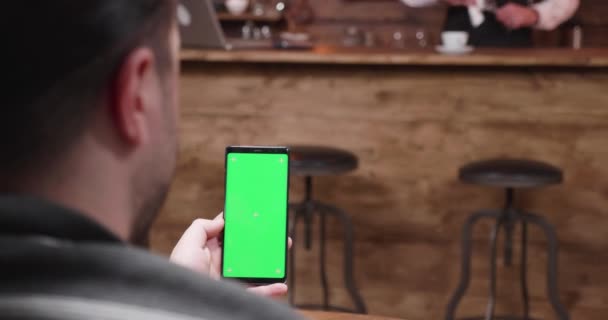 男人在带有绿色屏幕显示屏的手机上看和刷卡 — 图库视频影像