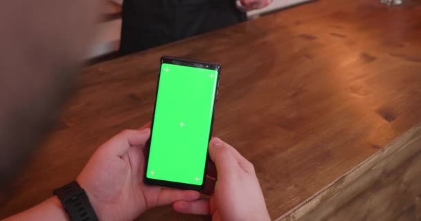 Muž v baru čítač drží telefon s zelená obrazovka — Stock video