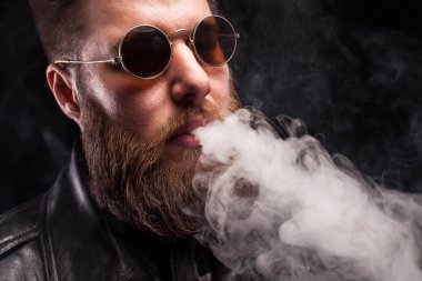 Sakallı adam deri ceket ve siyah arka plan üzerinde kahverengi güneş gözlüğü