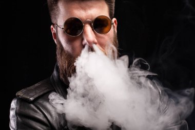 Siyah arka plan üzerinde sigara burnunda duman exhaling çekici sakallı adam