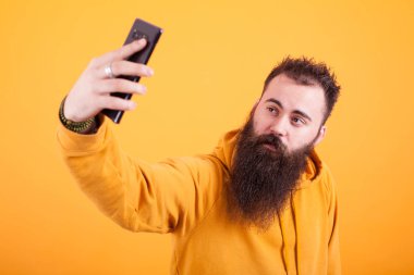 Sarı hoodie ve alma selfie sarı arka plan üzerinde giyen serin sakallı adam
