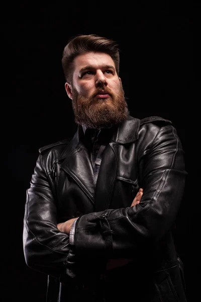 Portrait d'un bel homme barbu portant une veste en cuir avec une grave expresion sur fond noir — Photo