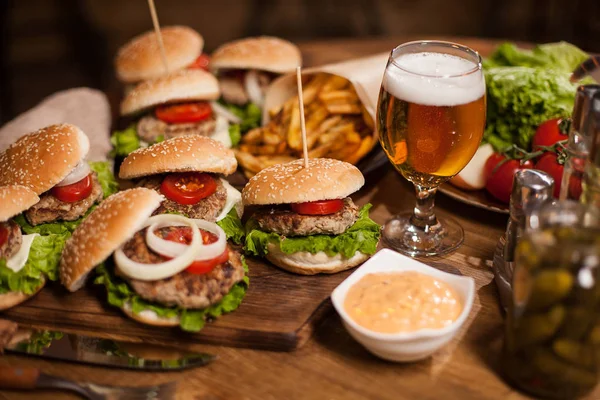 Close up of fresh burgers with a glass of beer on vintage wooden table — Stock Photo, Image