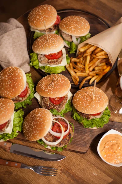 Blick von oben auf leckere Burger auf Holztafel neben Kochmesser — Stockfoto