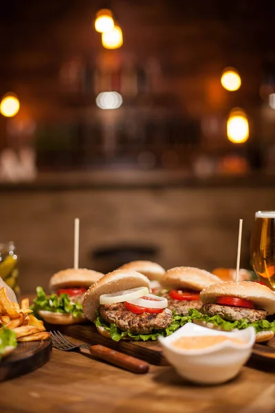 Hölzerner Restauranttisch voller köstlicher Burgres und Pommes. — Stockfoto