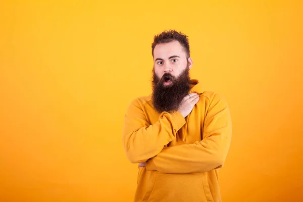 Retrato de belo hipster barbudo olhando espantado sobre fundo amarelo — Fotografia de Stock