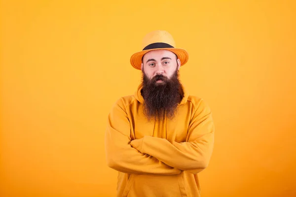 Hipster com barba longa usando um chapéu laranja sobre fundo amarelo — Fotografia de Stock