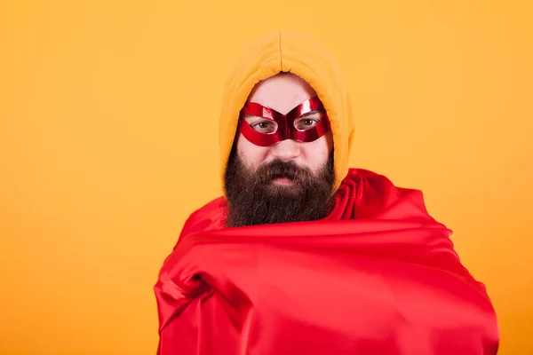 Super-herói barbudo com máscara vermelha mostrando sua capa vermelha sobre fundo amarelo — Fotografia de Stock