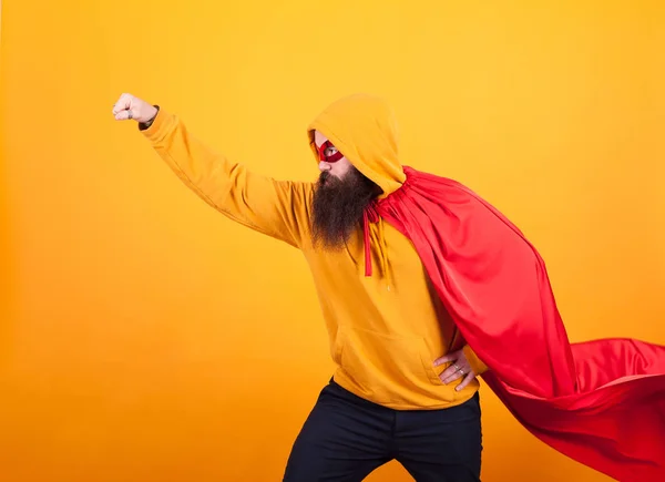 Superhéros avec cape rouge et masque s'envolant en studio sur fond jaune — Photo