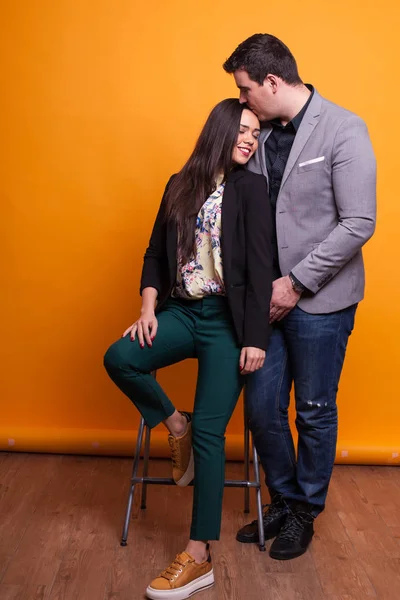 Esposo besando la frente de su esposa sobre fondo amarillo . —  Fotos de Stock