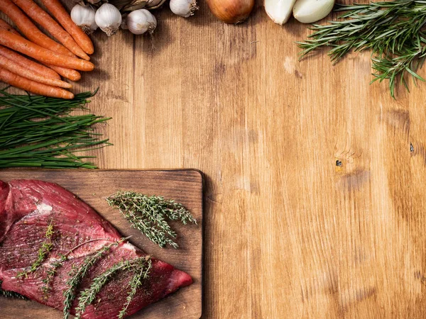 Vue du dessus de la viande rouge sur panneau de découpage avec du romarin à côté d'herbes vertes — Photo