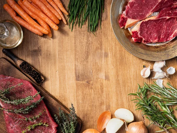 Vue de dessus d'un morceau de viande rouge sur une planche de cuisine en bois et deux morceaux de surlonge sur une assiette vintage — Photo