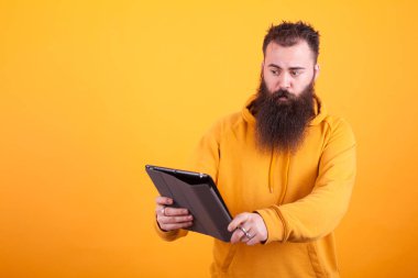 Hipster uzun sakallı tablet vasıl sarı arka plan üzerinde seyir