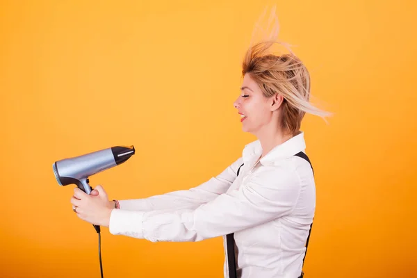 Komik kadın kısa saçlarını saç drayer ile sarı arka plan üzerinde üfleme. — Stok fotoğraf