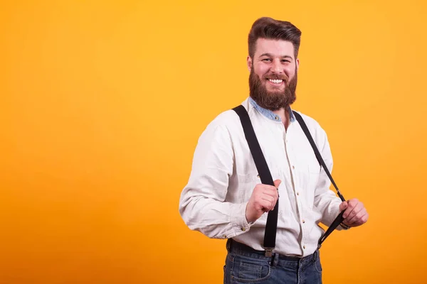 Hipster-Bärtiger zieht seine Lederhosen über gelben Hintergrund — Stockfoto