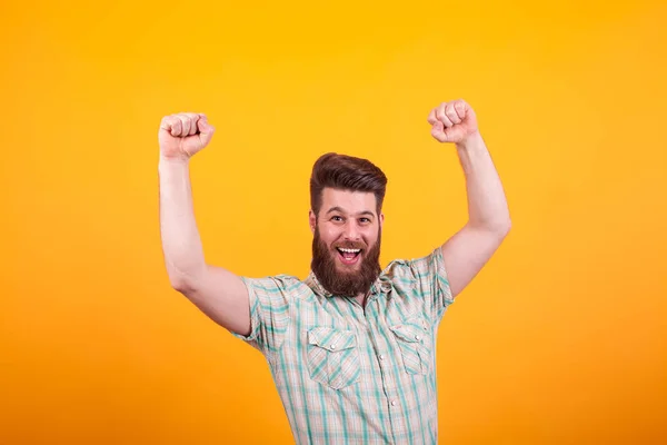 Portrait d'homme barbu heureux avec les poings vers le haut célébrant sur fond jaune — Photo