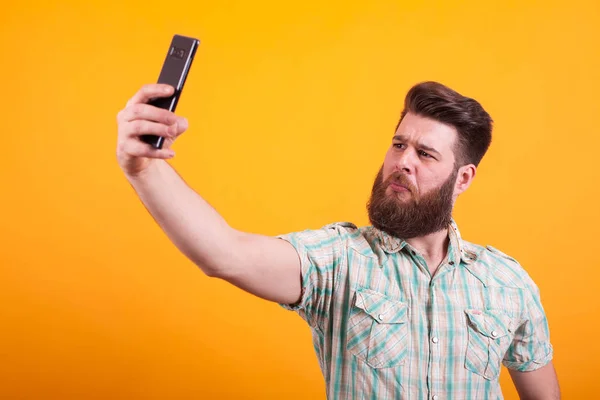 Atracție barbă om în cămașă luând un selfie peste fundal galben — Fotografie, imagine de stoc