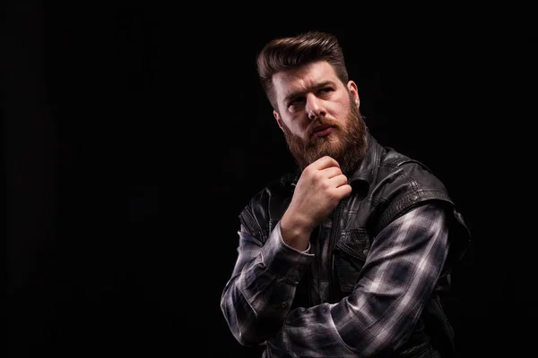 Retrato dramático de homem barba vestindo um colete de couro sobre fundo preto — Fotografia de Stock