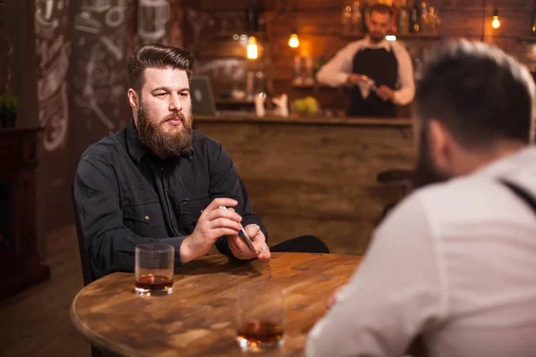 Hombres barbudos guapos jugando a las cartas en un pub y bebiendo whisky —  Fotos de Stock