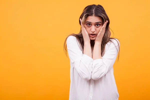 Portrait d'une jeune fille choquée en chemise blanche sur fond jaune — Photo