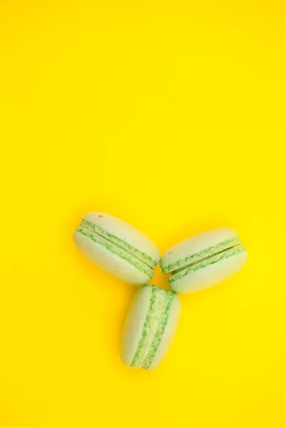 Bovenaanzicht van drie zoete bitterkoekjes op gele achtergrond — Stockfoto