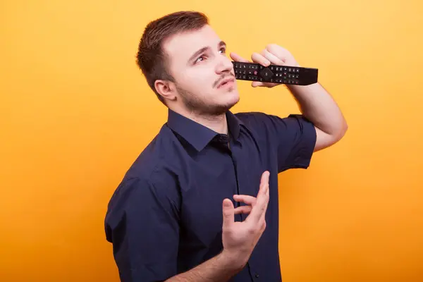 Junger Mann, der sich albern verhält und auf der Fernbedienung wie ein Telefon redet — Stockfoto