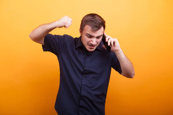 Junger Mann in Rage telefoniert auf gelbem Hintergrund — Stockfoto