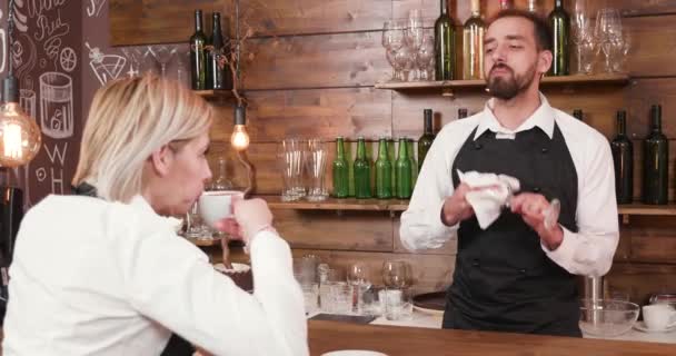 Bir cam temizlerken garson kıza erkek barmen konuşuyor — Stok video