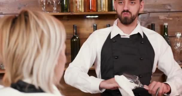 Schöner männlicher Barkeeper spricht mit seinem Mitarbeiter und putzt das Glas — Stockvideo