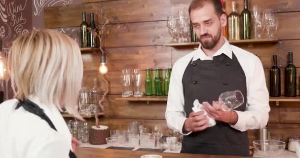 Pohledný mladý vousatý barman poslouchá servírka v baru — Stock video