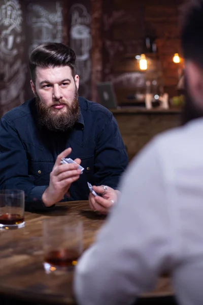Hombre barbudo guapo mirando a su amigo y barajar tarjetas — Foto de Stock