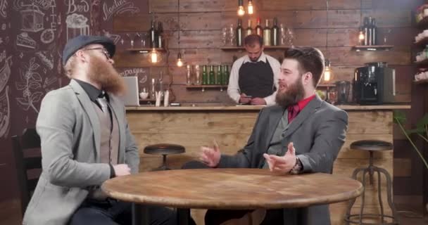 Два молодых стильных фрилансера общаются в маленьком винтажном кафе — стоковое видео