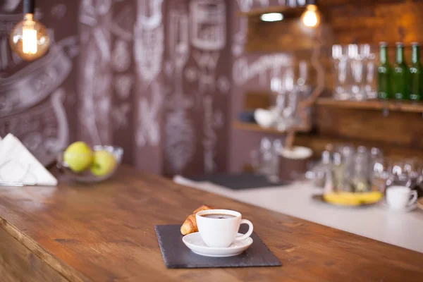 Чашка кофе рядом с французским десертом с художественным рисунком на заднем плане — стоковое фото