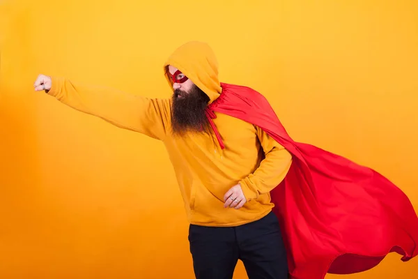 Hipster barbudo vestido com traje de super-herói voando para salvar o mundo ovr fundo amarelo — Fotografia de Stock