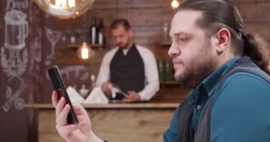 Uzun saçlı akıllı telefon kaydırma ile yakışıklı adam