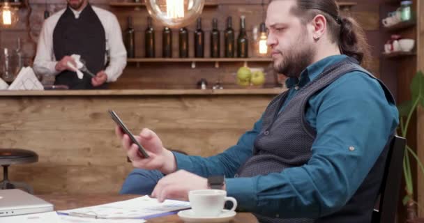 Hombre trabajando en su computadora desde un restaurante . — Vídeos de Stock