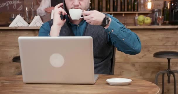 Όμορφος νέος ελεύθερος επαγγελματίας, πίνοντας καφέ στη μέση μια τηλεφωνική συνομιλία — Αρχείο Βίντεο