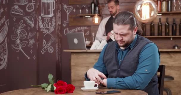 Красивый мужчина с длинными волосами ждет свою пару в ресторане — стоковое видео