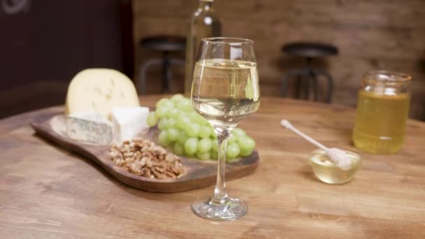 Cheese appetizers on a wooden table with wine and grapes — Stock Video