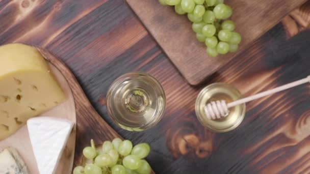 Blick von oben auf ein Glas Wein und verschiedene Käsesorten nebeneinander — Stockvideo