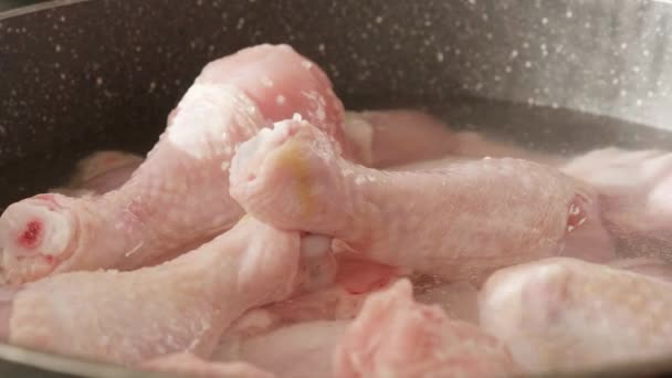 Pernas de frango cru lentamente cozinhando em água quente em uma panela — Vídeo de Stock
