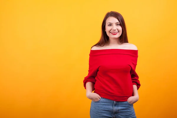 Glücklich schönes Mädchen mit Hosenträgern und langen Haaren auf gelbem Hintergrund — Stockfoto