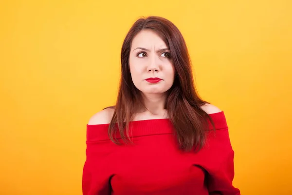 Schöne verwirrte Frau schaut weg über gelben Hintergrund — Stockfoto