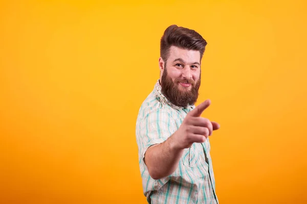 Hipster barbu homme pointant avec la main droite à la caméra sur fond jaune — Photo